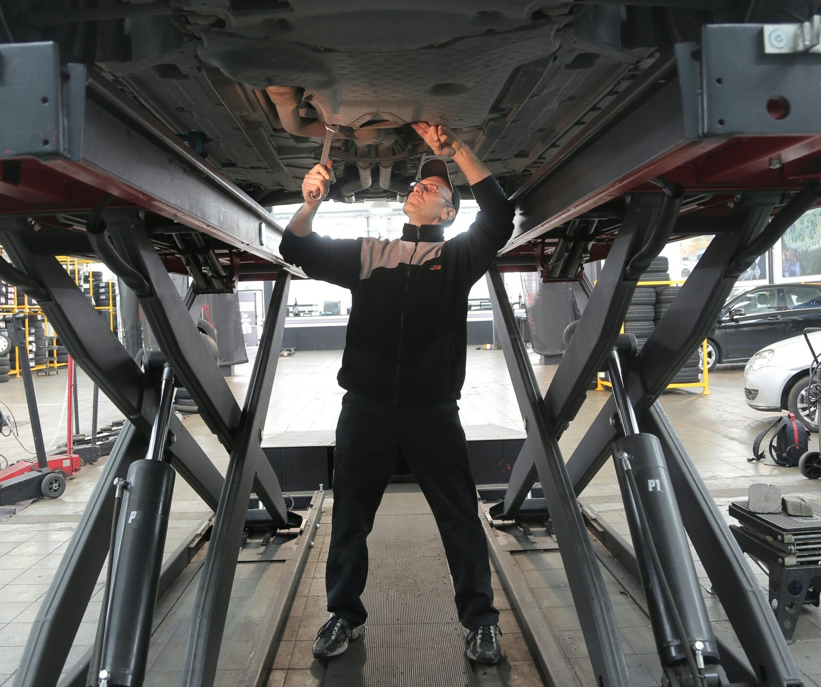Man in black jacket and black pants standing under vehicle