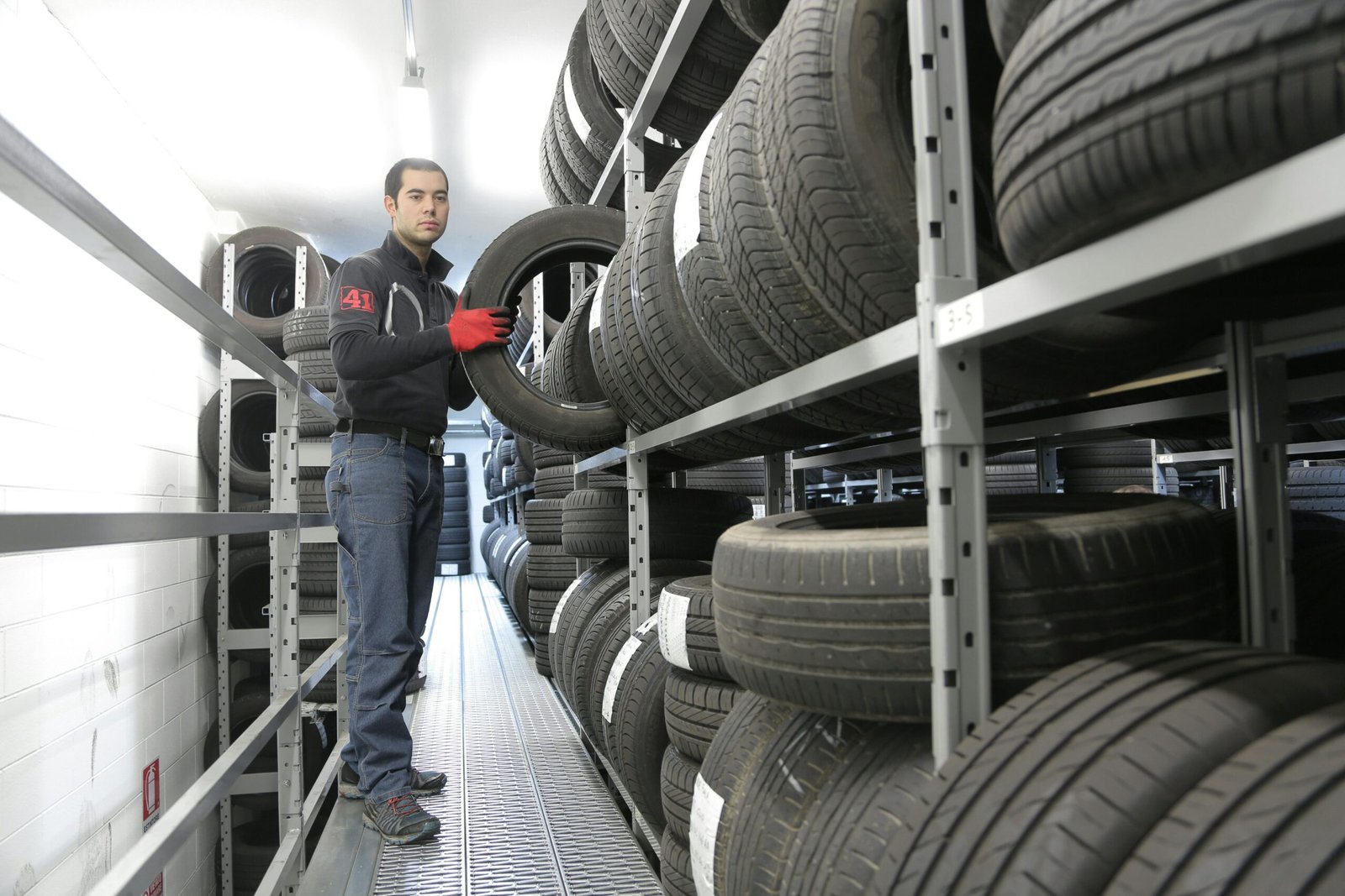Man in black jacket standing beside black tires